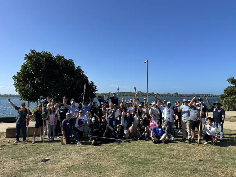 A large group cheering on the grass beside the water